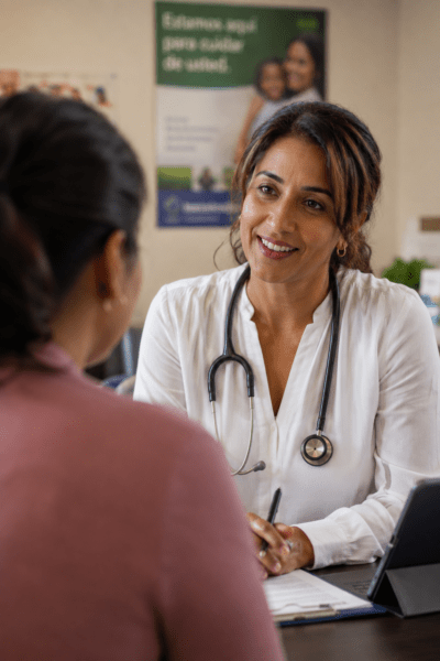 female FQHC doctor talking to patient in exam room