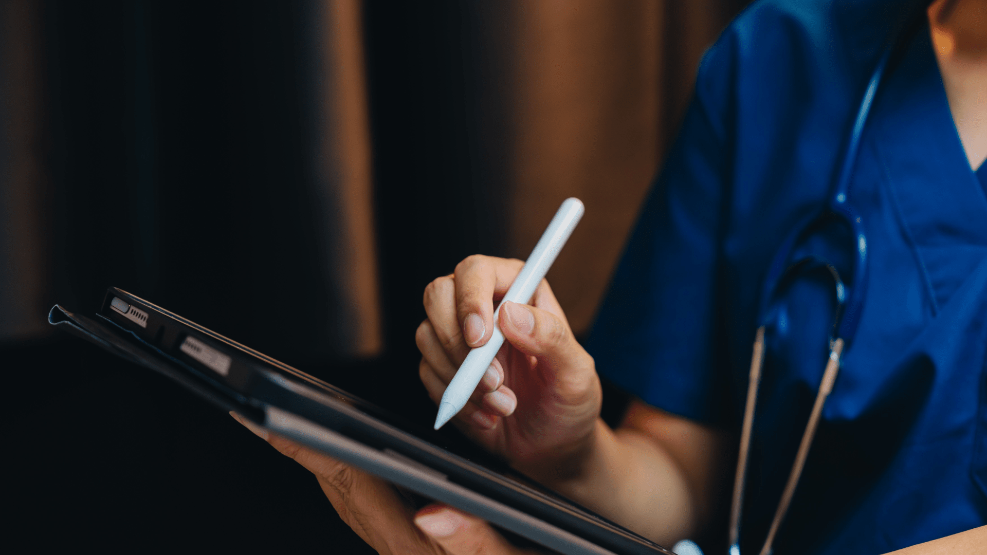 closeup of a doctor in blue scrubs using a tablet