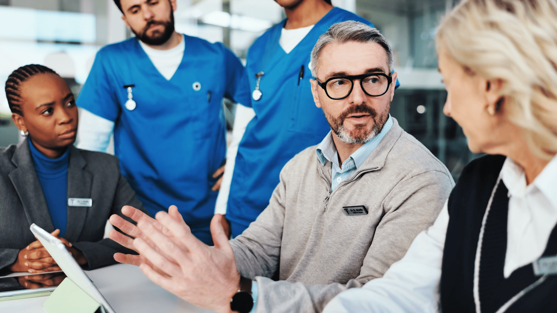 a doctor and team of medical professionals talking around a table